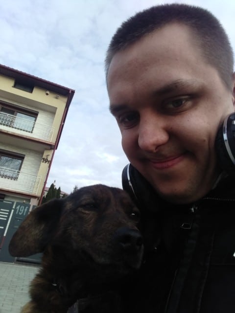 Tomasz Dziubak - uśmiechnięty młody człowiek z ciemnymi krótko ostrzyżony włosami z psem Lusią