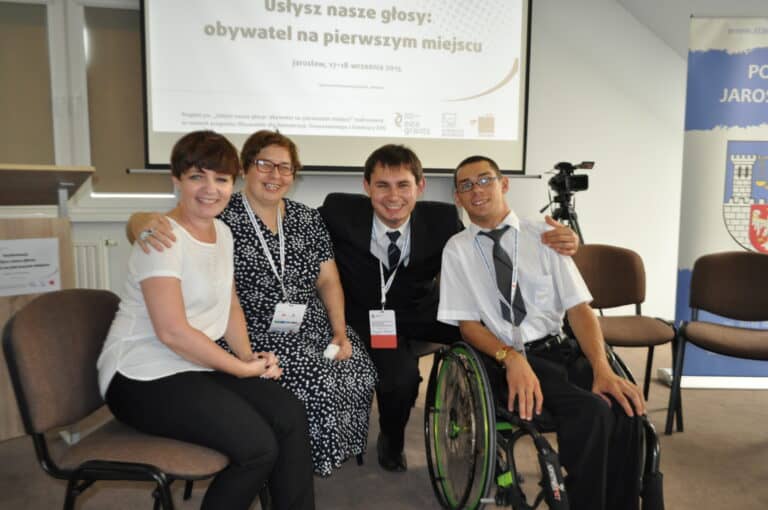 Po konferencji wraz innymi osobami na tle slajdu z tytułem wydarzenia