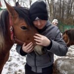 Młody mężczyzna przytula głowę konia