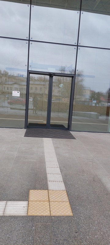 Jedno z wejść do nowego budynku dworca. Drzwi z kontrastową czarną ramą, ale bez pasków kontrastowych na szklanych taflach.