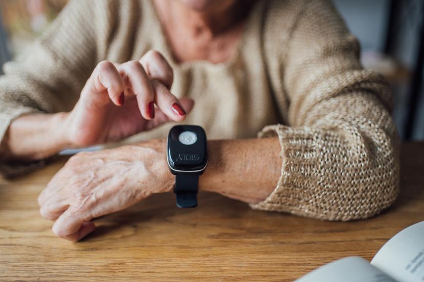 Ręce starszej pani, której na nadgarstku widnieje czarna opaska.