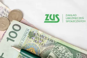 Banknot o nominale 100 zł i dwie monety o wartości 1 zł, długopis oraz dokument z logo i nazwą ZUS Zakład Ubezpieczeń Społecznych