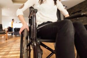 Kadr obejmujący kobietę siedzącą na wózku inwalidzkim od szyi w dół