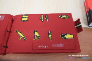 Wnętrze książki dotykowej pt. "Egyptian Hieroglyphs"; na karcie umieszczono zółte symbole, opatrzone Podpisem "Answer" w języku angielskim oraz Braille'u