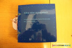 Granatowa okładka książki dotykowej pt. "Kilka słów o planetach", Autorzy: tekst- Wiktoria Bujak, ilustracje Milena Piędzia, Paulina Romanowska