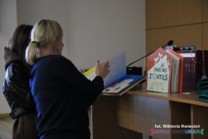 Dwie kobiety oglądają nagrodzone i wyróżnione książki dotykowe