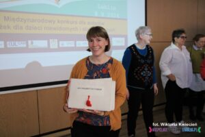 Jedna z Jurorek prezentuje okładkę książki pt. Les Chaussettes d’Oscar; kobieta uśmiecha się