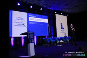 Na scenie stoi Pan Andrzej Rybus-Tołłoczko - Zastępca Dyrektora Narodowego Instytutu Wolności podczas prelekcji pt. "Finansowanie NGO ze środków NIW"