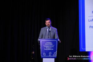 Przy mównicy stoi Pan Łukasz Chlebny, moderator debaty eksperckiej pt. "Każda organizacja pozarządowa powinna zarabiać"