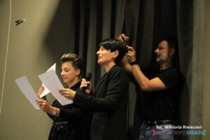 Odczytanie wyników Konkursu, od lewej stoją Panie: Karolina Czajka i Kinga Hendzel - za nimi stoi mężczyzna, który robi zdjęcia