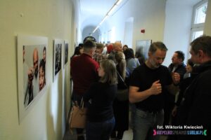 Na ścianie po lewej stronie wąskiego korytarza wiszą zwycięskie fotografie TwO, oglądane przez tłumnie zgromadzonych Gości