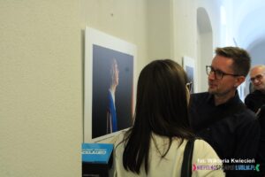 Dwie osoby oglądają wiszącą na ścianie fotografię Magdaleny Wojtachnio-Przerady pt. Manifestor (I miejsce w kategorii Portret)