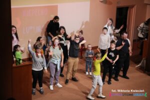Finał koncertu; na scenie grupa dzieci i opiekunów we wspólnym tańcu