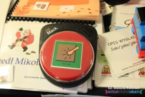 Komunikator BigMack; plastikowy przyrząd z dużym czerwonym przyciskiem i naklejonym piktogramem przedstawiającym pukającą dłoń i napis "puk, puk"