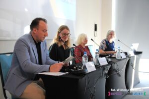 Od lewej przy stole siedzą: Pan Tomasz Osiecki – Doradca Biznesowy i Kluczowy w Ośrodku Wsparcia Ekonomii Społecznej, EDS-FNS. Pani Małgorzata Śmiegiel – Dyrektor Biura Stosunków Międzynarodowych na Uniwersytecie Abat Oliba CEU w Barcelonie (Hiszpania), Pani Małgorzata Filipowicz – Psycholog, Specjalistka ds. Zarządzania Rehabilitacją w Zakładzie Aktywności Zawodowej w Charytatywnym Stowarzyszeniu Niesienia Pomocy Chorym “Misericordia” oraz Pani dr L’ubica Černá – Prezes NKOS (Słowacja)