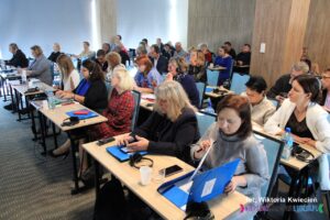 Widok na zgromadzonych na sali uczestników konferencji, siedzących w dwuosobowych ławkach