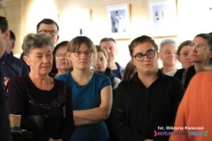 Grupa uczestników wernisażu, z przodu stoją trzy kobiety