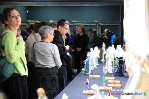 Ludzie oglądają stojące na długim blacie figurki Aniołów