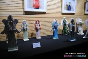 Na blacie stoją różnokolorowe drewniane figury Aniołów, wykonane w ŚDS w Łęcznej w ramach warsztatów “Anielskie rękodzieło” – instruktor: Joanna Kłębokowska, Rafał Bojarczuk