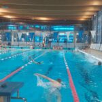 Zbliżenie na basen, w którym zawodnicy rozgrzewają się, płynąc w stronę siebie.