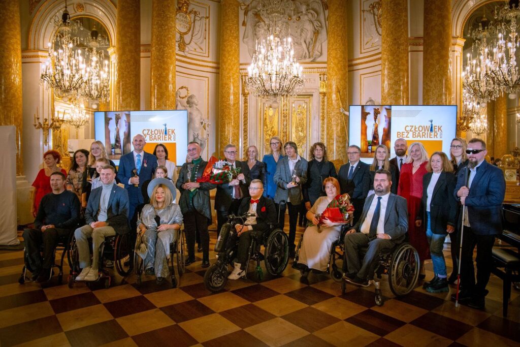 W Sali balowej Zamku Królewskiego w Warszawie stoją razem laureaci i uczestnicy Gali Konkursu Człowiek bez barier 2024.