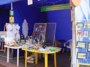 Pod granatowym namiotem na dwóch plastikowych stołach wyeksponowano prace plastyczne i rękodzieło