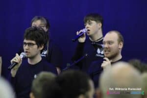 śpiewający członkowie zespołu „Rozśpiewany Zakątek”; widok z widowni