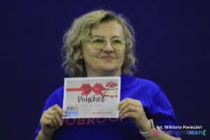 Kobieta w średni wieku trzyma w rękach licytowany Voucher na tort