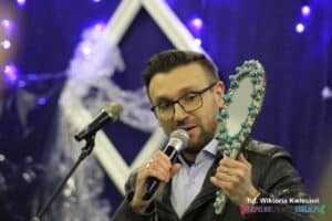 Mężczyzna z mikrofonem prezentuje licytowany przedmiot - ręcznie zdobione lusterko