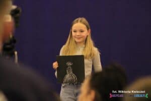 Ręcznie malowany obraz z wizerunkiem kobiety, prezentowany przez nastoletnią autorkę