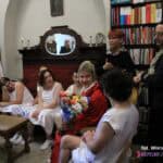 We wnętrzu księgarni siedzą aktorzy w strojach scenicznych, po lewej stronie stoją Maria Pietrusza-Budzyńska i Paweł Passini