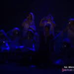 Sylwetki kobiet pogrążonych w mroku, na scenie skąpo oświetlonej niebieskim światłem