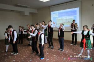 Grupa uczennic i uczniów szkoły, ubranych w stroje ludowe podczas występu tanecznego