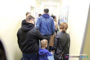 Grupa zwiedzających osób obu płci w wąskim korytarzu