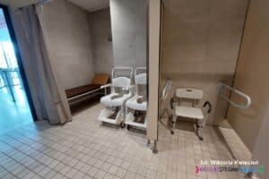 Aqua Lublin: zagospodarowana wnęka z zasłonką, wyposażona w leżankę, obok ustawiono dwa wózki ociekowe; w kabinie obok pomiędzy przymocowanymi do ściany pochwytami stoi krzesło prysznicowe