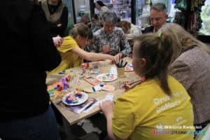 Do stołu pełnego materiałów plastycznych przysiedli się dyrektorzy i urzędnicy, którzy odwiedzili stoisko warsztatowe, aby wspólnie z uczestnikami rysować zakładki do książki w kształcie skarpetek