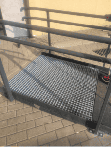 Platforma podjazdowa w formie metalowej kratki, wyposażona w poręcze