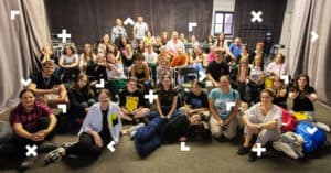 Grupa młodych osób siedząca w półkolu w pomieszczeniu