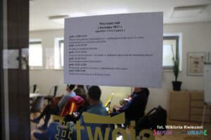 Karta z harmonogramem warsztatów prowadzonych w dniu 2 kwietnia wisząca na przeszklonych drzwiach sali na I piętrze