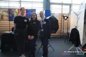 Na zdjęciu widoczna jest trójka młodych kobiet, które pozują do aparatu. Są to słuchaczki Policealnego Studium Animatorów Kultury w Krośnie, studiujące na kierunku Animator fotografii. W tle przygotowano stanowisko do nieodpłatnego wykonania zdjęć do CV, które było częścią oferty szkoły na targach