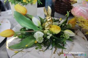 Stroik wielkanocny ze złotym zającem i żółtymi kwiatami na stoisku Warsztatów Terapii Zajęciowej w Bobrowej Woli