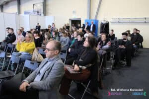 Uczestnicy kongresu siedzący na widowni. Zdjęcie ukazuje rzędy krzeseł i uczestników uważnie słuchających