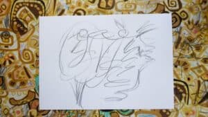 Arkusz białego papieru z abstrakcyjnymi szkicami ołówkiem, położony na kolorowym, wzorzystym tle z tkaniny