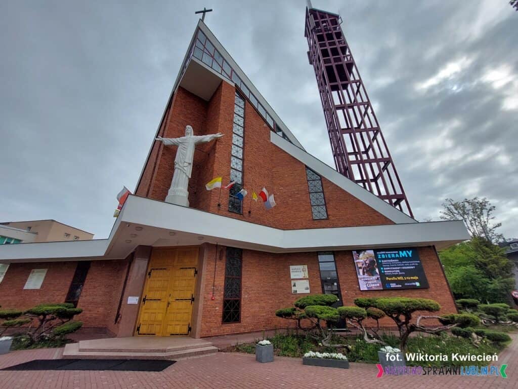 Bryła kościoła pw. Najświętszego Serca Jezusowego w Lublinie według projektu Mirosława Załuskiego. Nowoczesny budynek z wysoką dzwonnicą i rzeźbą Jezusa umieszczoną na fasadzie
