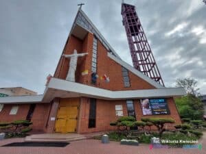 Bryła kościoła pw. Najświętszego Serca Jezusowego w Lublinie według projektu Mirosława Załuskiego. Nowoczesny budynek z wysoką dzwonnicą i rzeźbą Jezusa umieszczoną na fasadzie