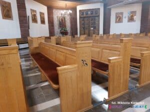 Wnętrze kościoła. Środkowy rząd ławek z oznaczeniem systemu pętli indukcyjnej granatowym symbolem: ucha z przekątną linią i literą „T”