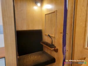 Wnętrze zamykanego konfesjonału po stronie spowiednika. Na pulpicie widoczny mikrofon podłączony do systemu pętli indukcyjnej