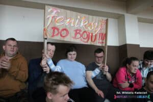 Kibice siedzący na trybunach z transparentem "Feniksy do boju!!!"