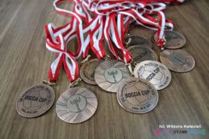 Na drewnianym blacie ułożono metalowe medale z napisem "VIII Akademicki Turniej 'Boccia Cup 2025'. Lublin, 08.05.2025"
