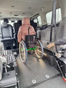 Fragment wnętrza samochodu w którym siedzi osoba na wózku inwalidzkim znajdujący się przed nią fotel pasażera jest zwrócony frontem w jej kierunku